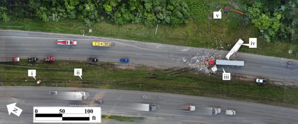 Aerial view of a multi-lane highway with several vehicles and scattered debris, labeled i, ii, iii, iv