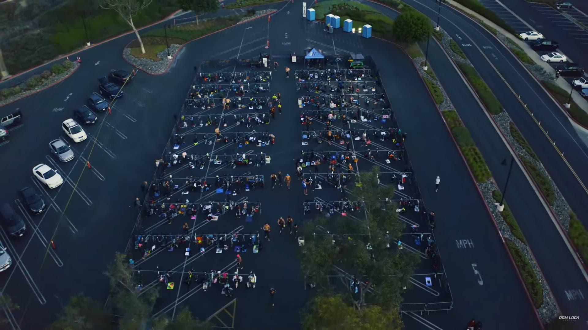 Drone view of a large outdoor event in a parking lot with rows of seating on scaffolding