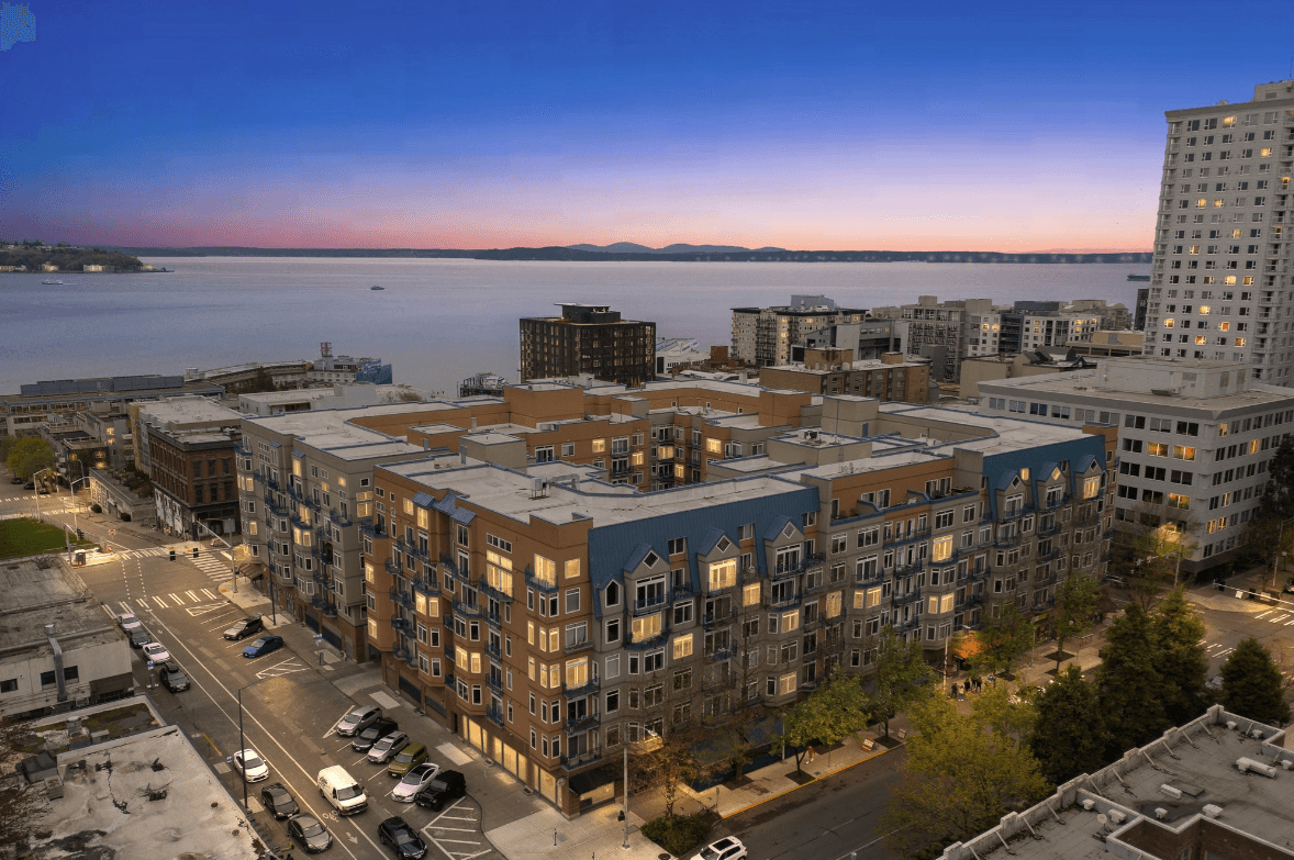 Aerial view of a waterfront city with modern apartment buildings, streets and a calm bay at dusk