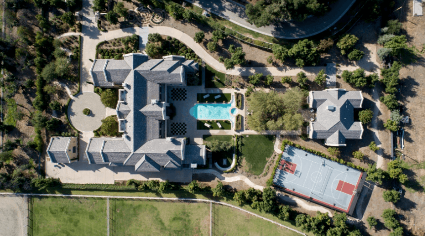 Aerial view of a large estate with a pool, circular feature, curved driveways, and a basketball court